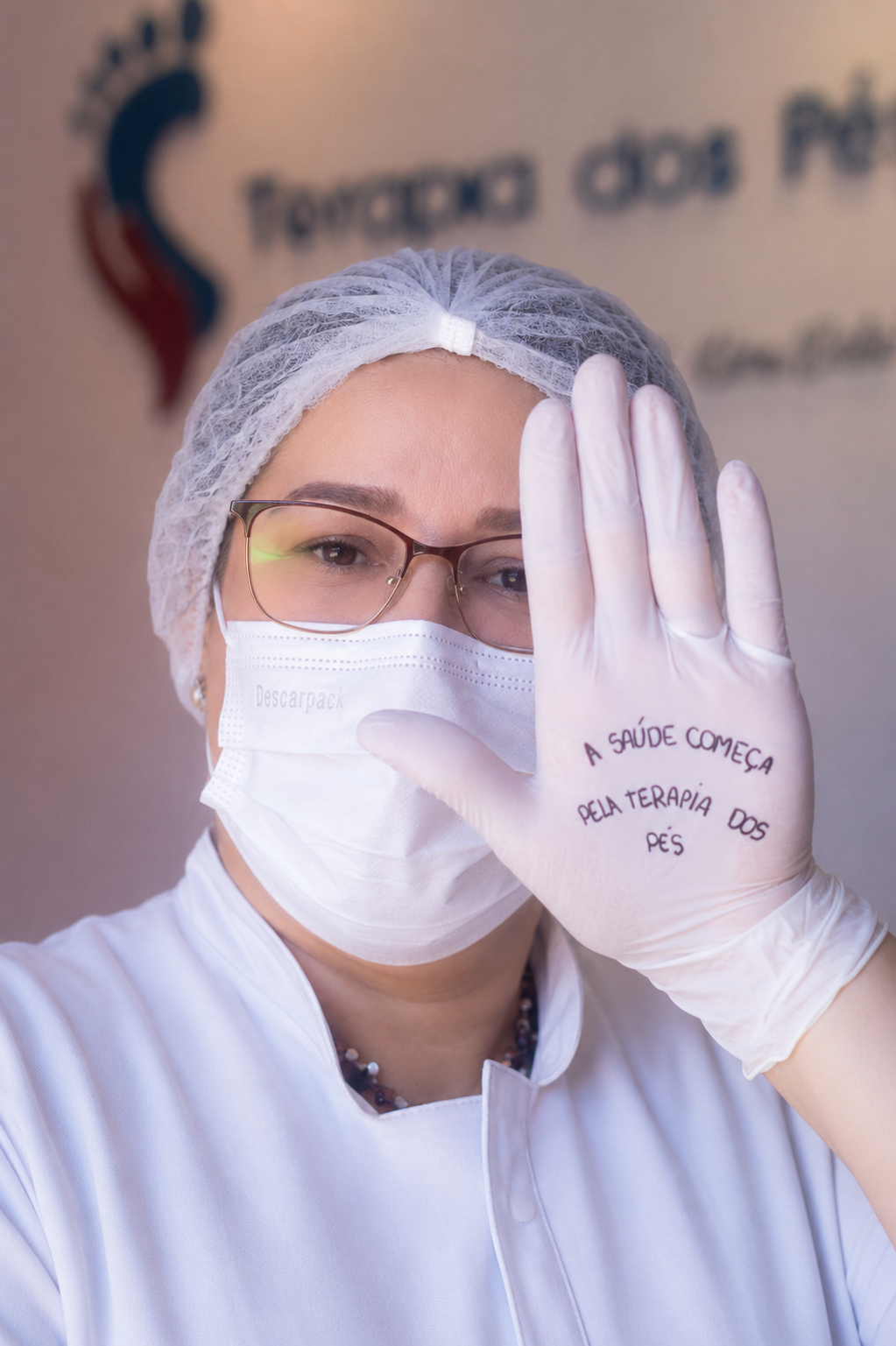 Daniele com EPI mostrando a mensagem: a saúde começa pela terapia dos pés